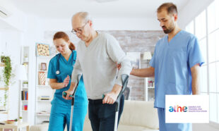An elderly person using crutches, assisted by two healthcare professionals in a bright living room.